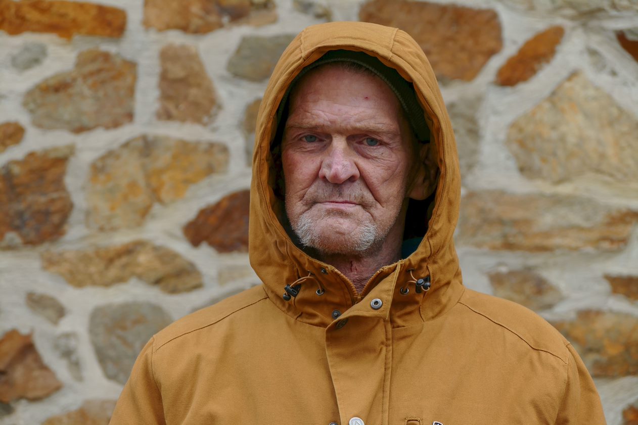 homeless man standing in front of wall