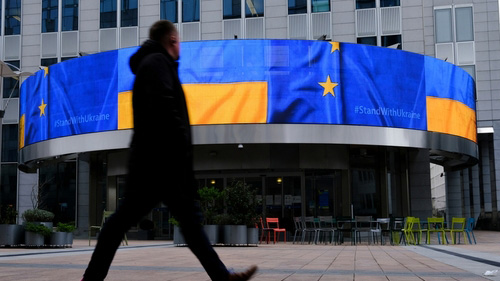 man walking by EU and ukraine flags