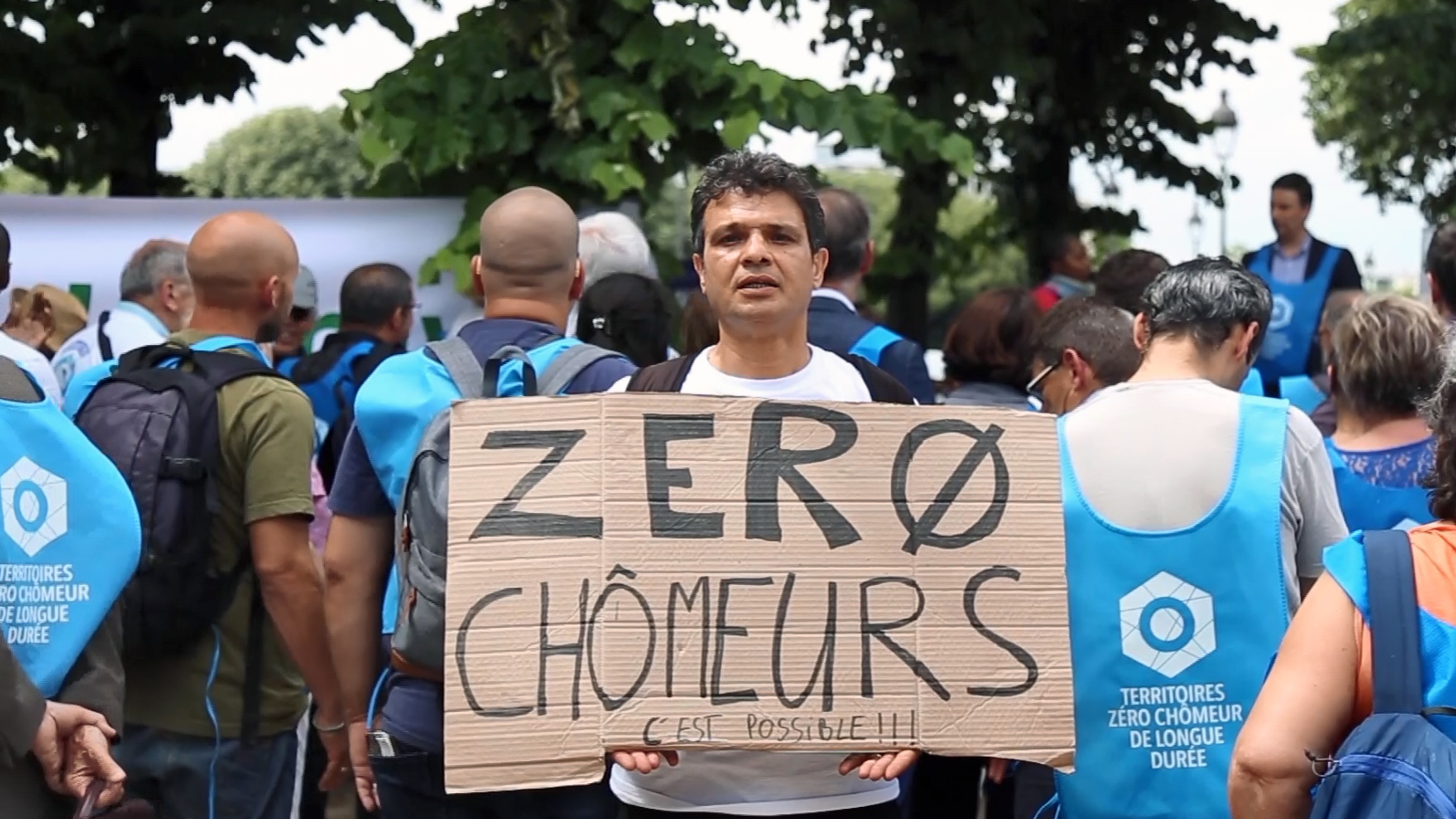 A man showing a message calling for zero long-term unemployment