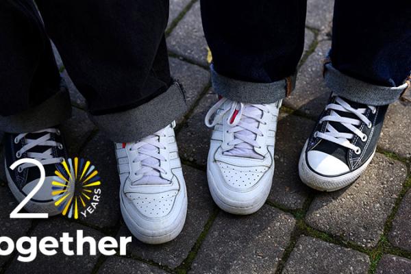 Two people wearing mismatched shoes, as part of the "stepping into another's shoes" campaign
